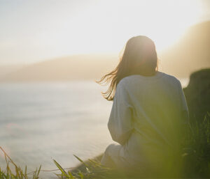 Lady on seashore looking at sunset