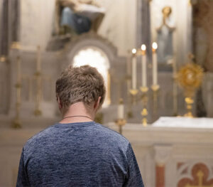 Young man spending an hour of adoration before the exposed Blessed Sacrament